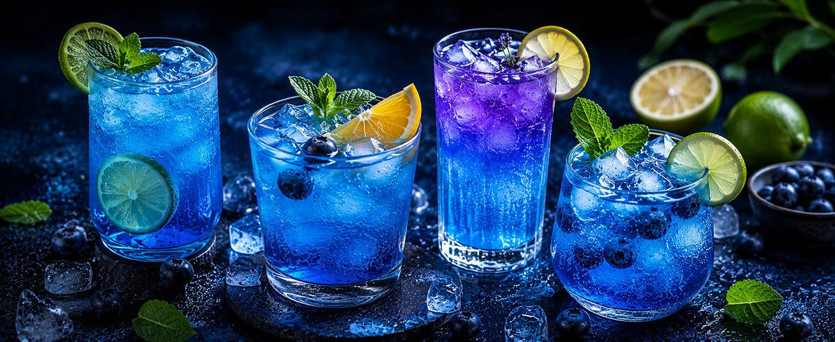 Cuatro mocktails y limonadas de color azul con guarniciones cítricas, coloreados con espirulina azul