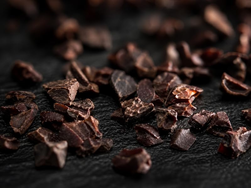 Trozos de nibs de cacao crudo sobre una superficie oscura