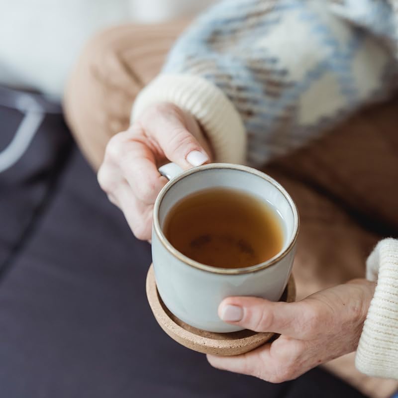 Taza de infusión de hierbas de neem caliente sostenida con ambas manos